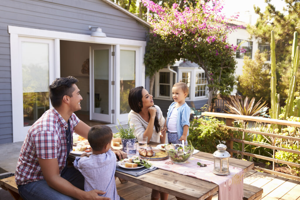 Family At Home Eating Outdoor Meal In Garden Together
